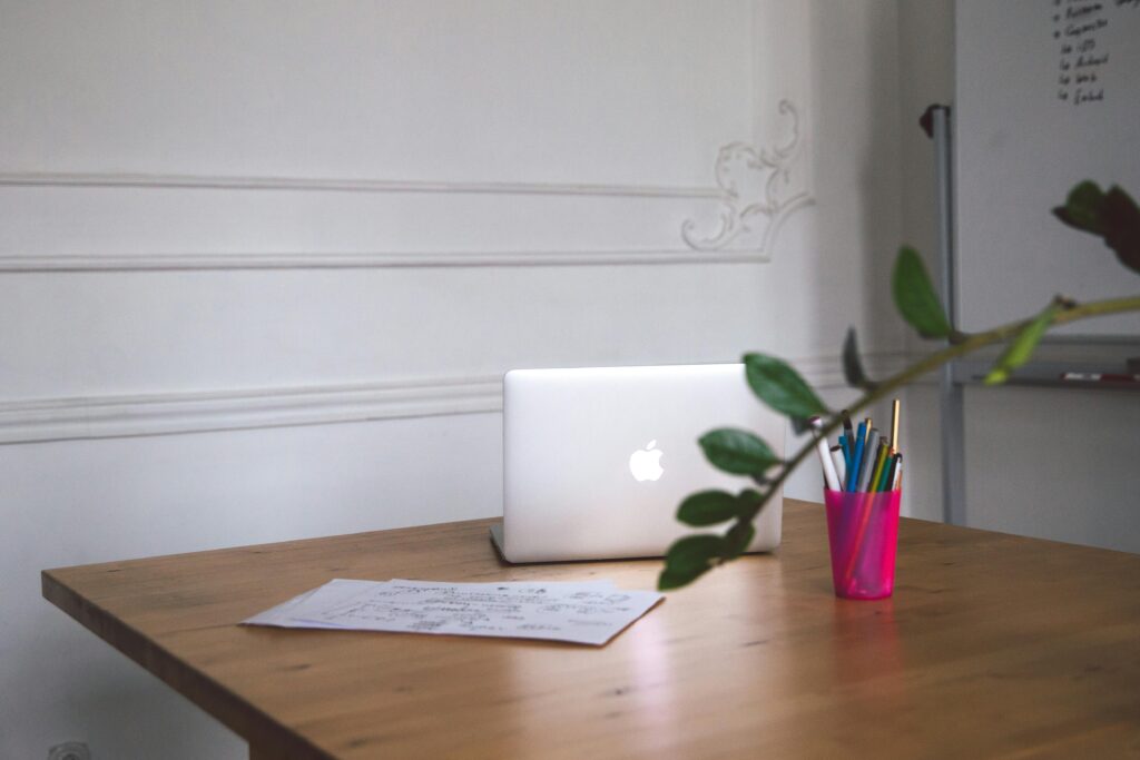 A clean desk with a laptop, notes, and pens creating a modern workspace.